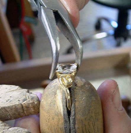 A stone being set in a ring at the bench