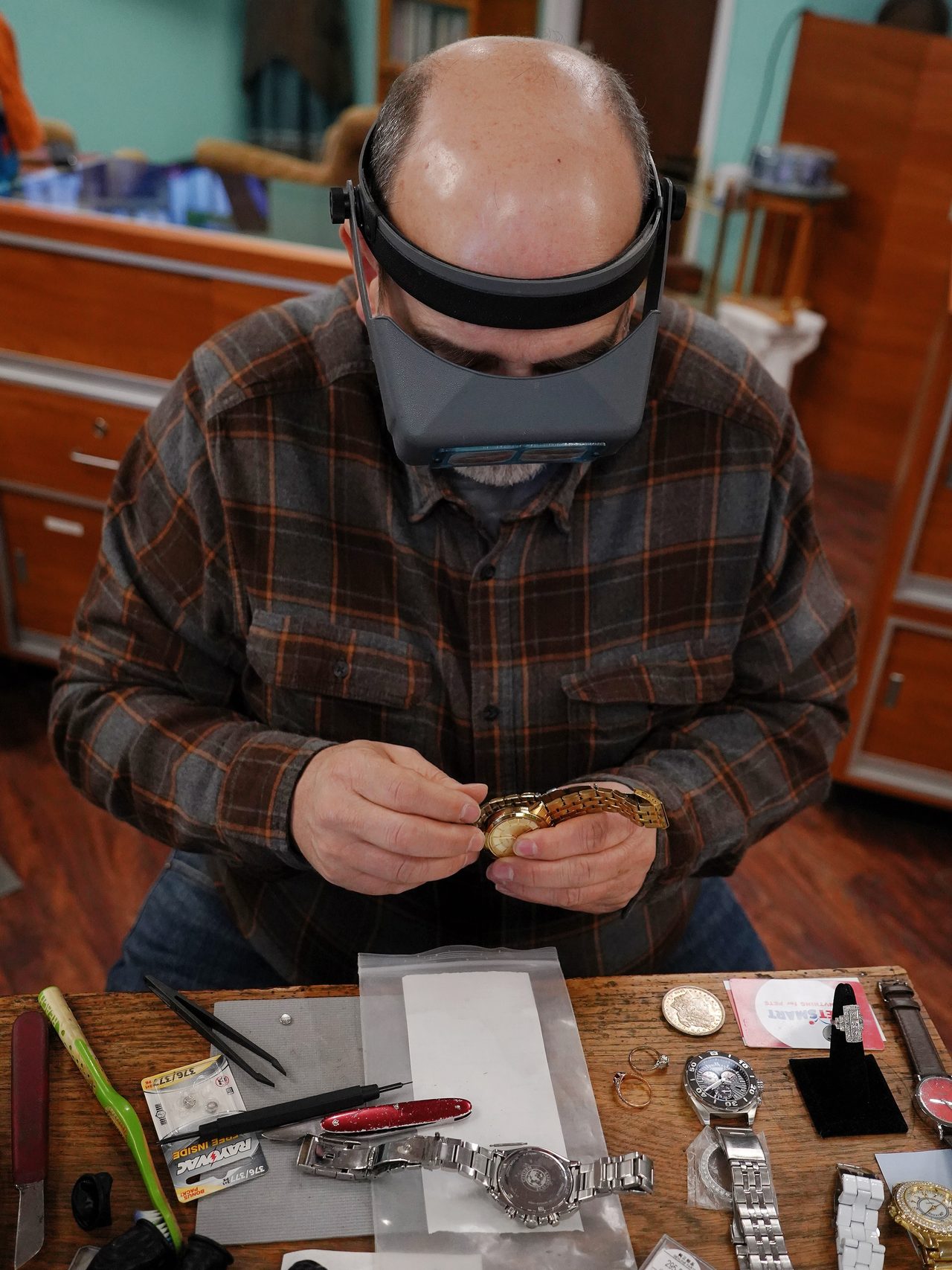 A jeweler working at the bench with watches and rings